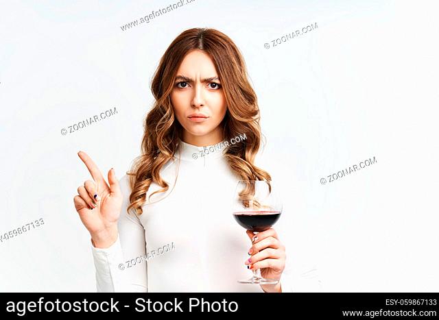 Young pretty woman refuse to drink alcohol holding glass of red wine on white background. stop alcoholism