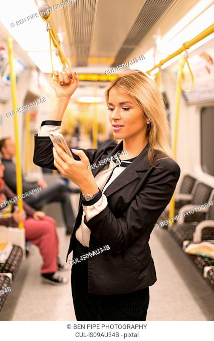Businesswoman texting on tube, London Underground, UK