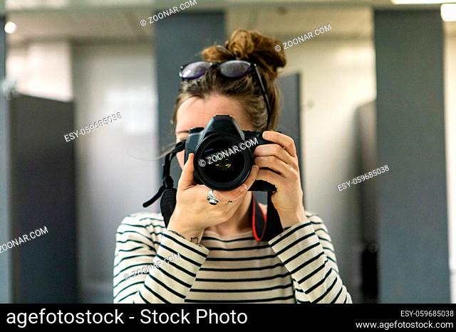 A close up and front view of a young Caucasian woman taking a photograph behind a professional camera. Looking straight into the lens with room for copy