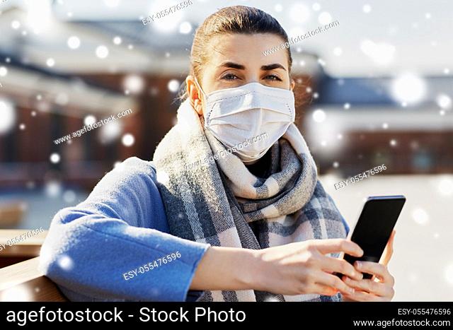 woman in face mask with smartphone in city