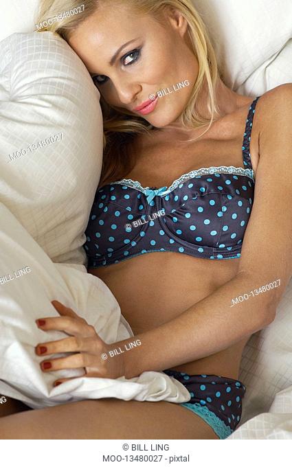 Woman wearing underwear lying on bed portrait