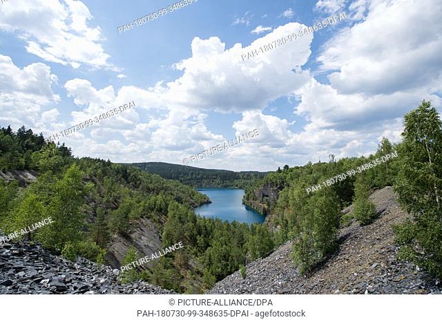 27 July 2018, Germany, Lehesten: View of the slate lake near Lehesten. The lake was created after slate mining was stopped and the open-cast mine was filled...