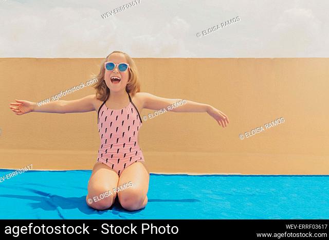 Portrait of happy girl wearing pink sunglasses and swimsuit having fun on roof terrace