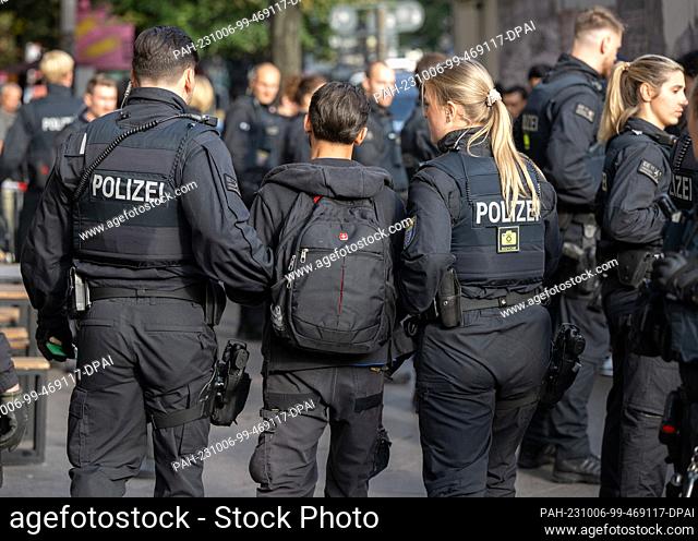 06 October 2023, Hesse, Frankfurt/Main: Officers of a police unit take away a suspect in the station district of Frankfurt am Main