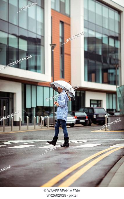 Woman holding umbrella and crossing street