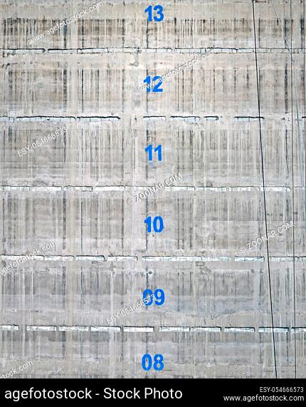 the surface of a concrete service tower core of a building under construction with the floor numbers marked in blue paint