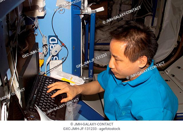 Astronaut Edward T. Lu, Expedition 7 NASA ISS science officer and flight engineer, uses a computer in the Destiny laboratory on the International Space Station...
