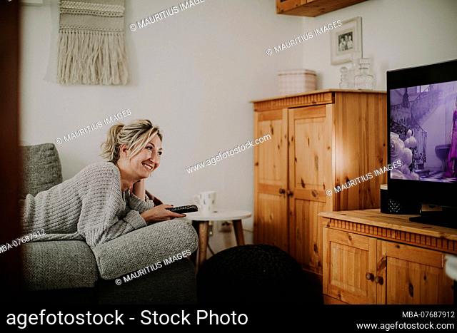 Woman lies relaxed on the couch while watching TV