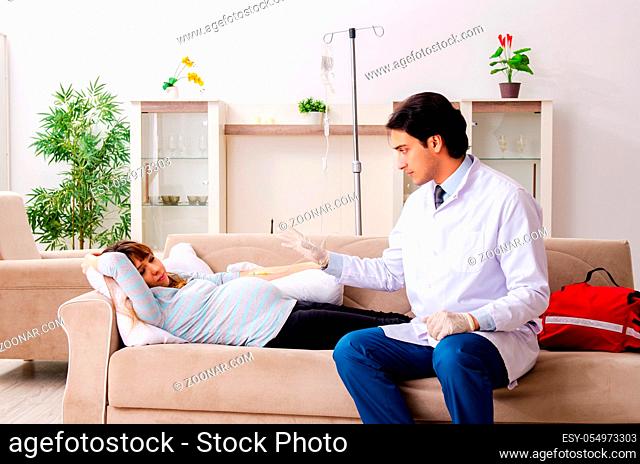 Young handsome doctor visiting pregnant woman at home