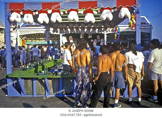 Carny game on Santa Monica pier with tourists, Sunday afternoon, Los Angeles, CA