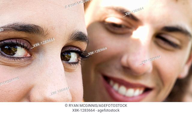 A woman's eyes look left as her husband looks at her from the background
