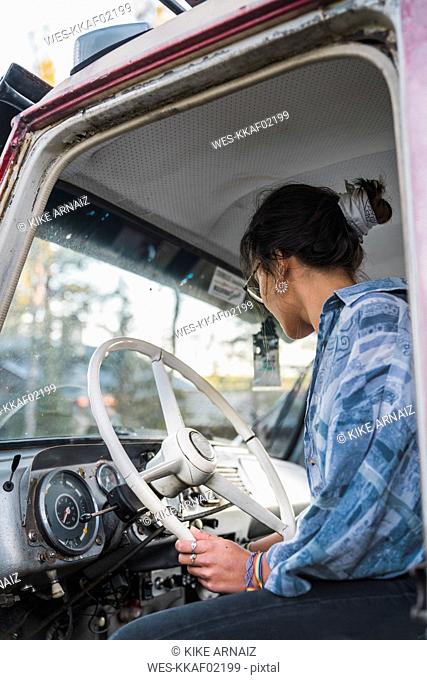 Young woman sitting in cabin of a broken vintage truck