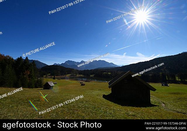 17 October 2022, Bavaria, Gerold: The sun shines over the meadows at Geroldsee, the Karwendel mountains can be seen in the background