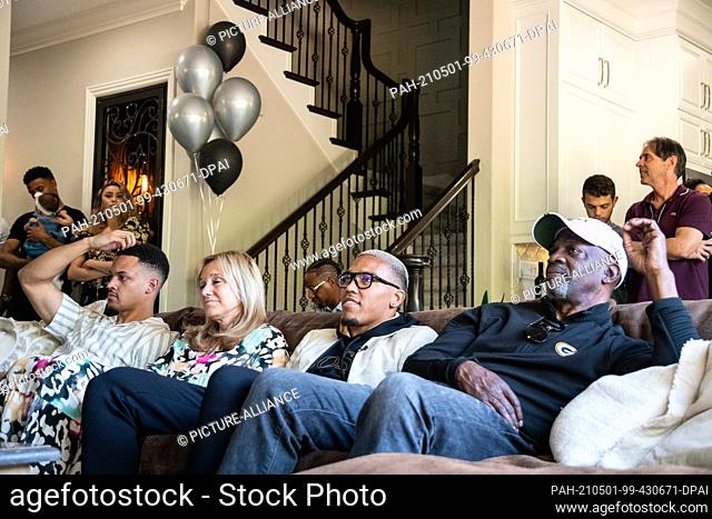 30 April 2021, US, Lake Forest: Amon-Ra St. Brown (2nd from right) sits on a couch between his mother Miriam Brown and father John Brown during the NFL draft