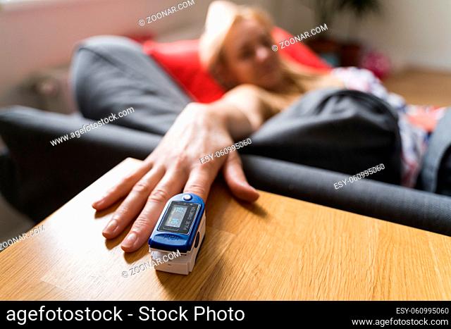 Middle age woman at home checking blood oxygen level with pulse oximeter. Coronavirus covid symptoms. Asthma, lungs decease. High quality photo