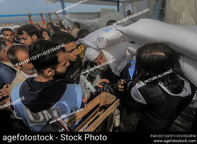 22 November 2023, Palestinian Territories, Khan Yunis: Palestinians receive bags of flour at the United Nations Relief and Works Agency for Palestinian Refugees...