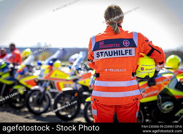 06 April 2023, Lower Saxony, Laatzen: A volunteer traffic jam helper stands in front of motorcycles of the Johanniter motorcycle squad at the ADAC traffic...