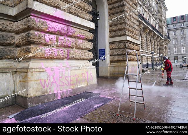 26 May 2021, Hamburg: A facade cleaner removes pink paint from the entrance portal of the city hall on the Rathausmarkt. A supporter of the climate protection...