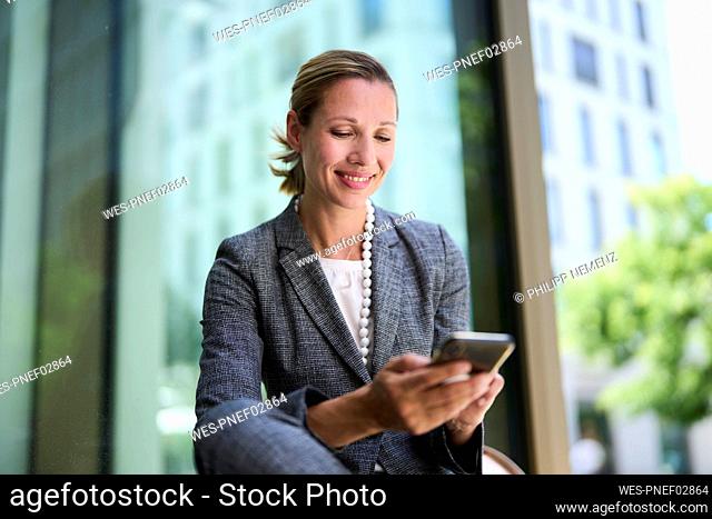 Smiling businesswoman text messaging through smart phone
