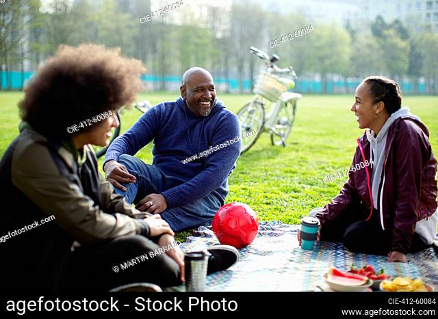 Happy father and teen kids enjoying picnic in urban park