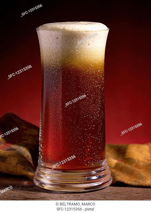 A glass of cold ale with foam on top