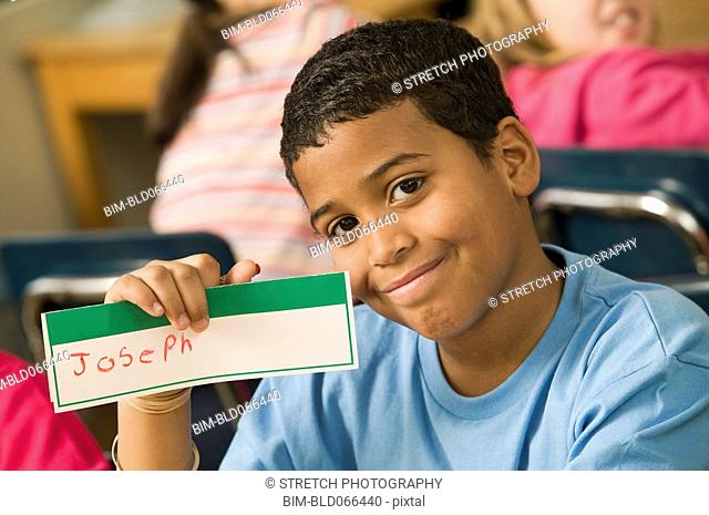 Mixed race school boy holding name card