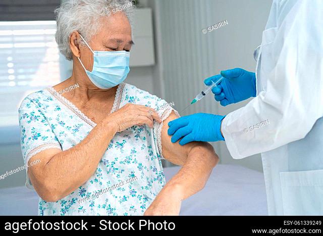 Elderly Asian senior woman wearing face mask getting covid 19 or coronavirus vaccine by doctor make injection