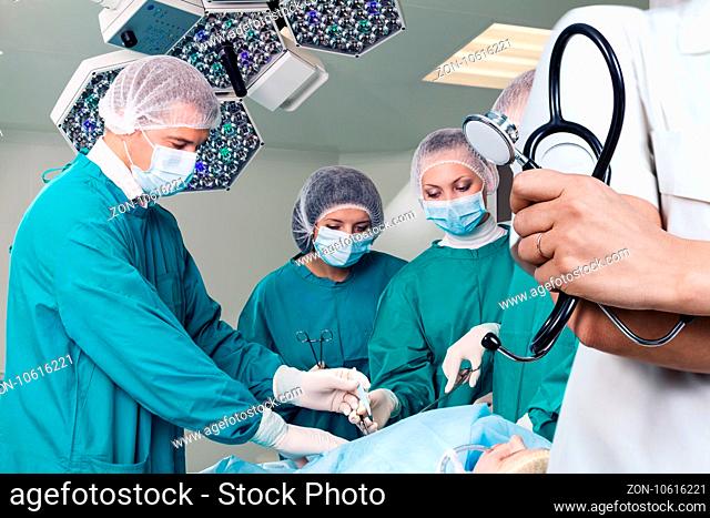 Doctor holding stethoscope over surgeons team during a surgery