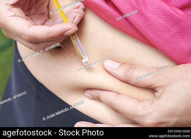 Woman is doing an heparin injection in her abdomen at home