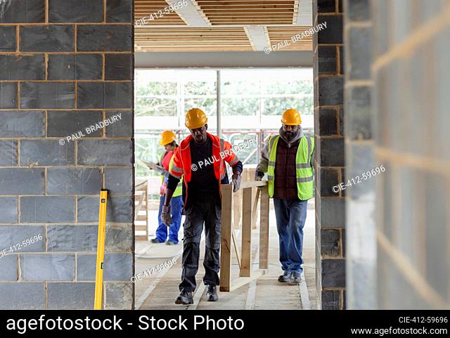 Construction workers carrying wood frame at construction site