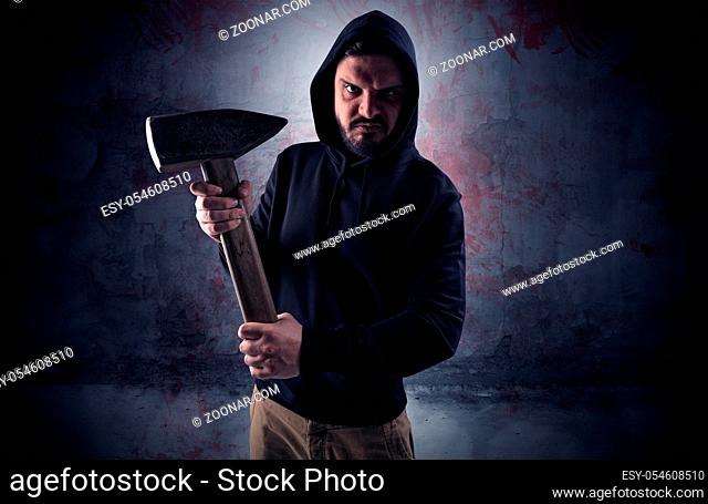 Armed rude assassin in an empty bloody room concept with gun ax chainsaw mallet wrench