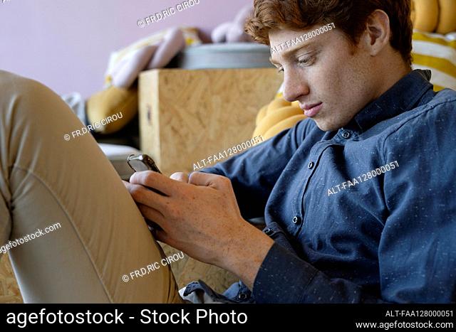Side view of young man using smart phone in office