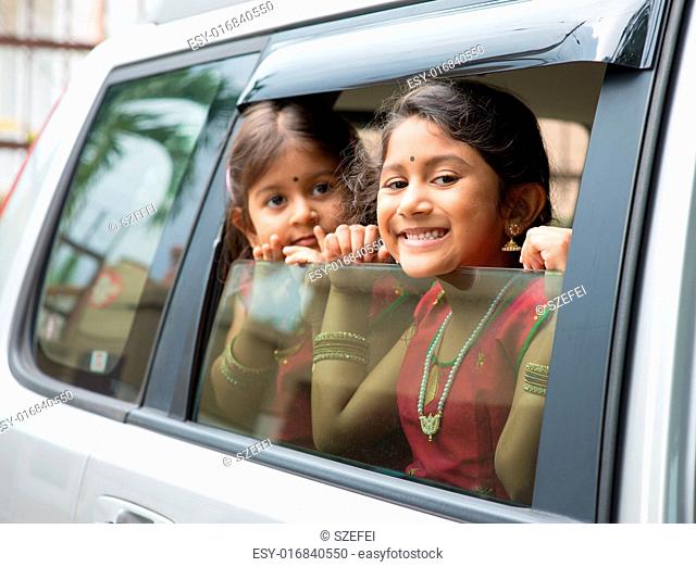 Asian Indian family going to a vacation. Happy children sitting inside car with window open looking out