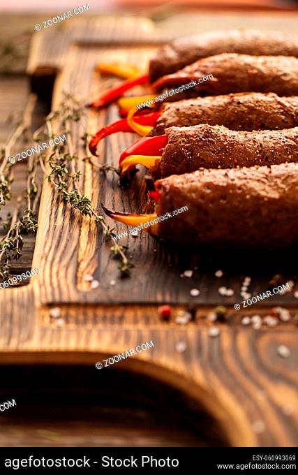 Meat rolls stuffed with sweet red and yellow paprika on a wooden serving board