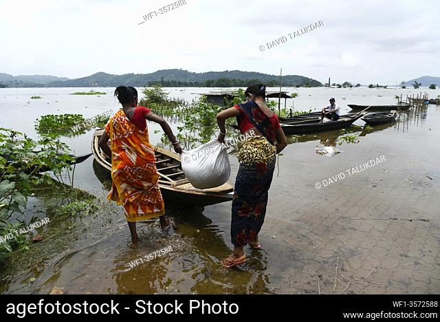 Villagers waking wade through a flooded road, in Kamrup district of Assam, Monday, July 13, 2020