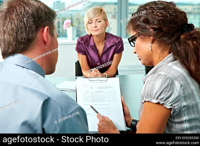 Woman applicant worrying during job interview. Over the shoulder view. Focus placed on sheet in front results are good