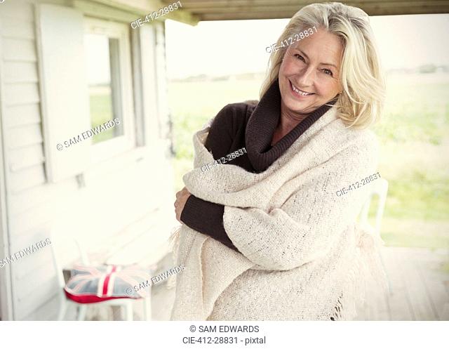 Portrait smiling senior woman wearing shawl on porch