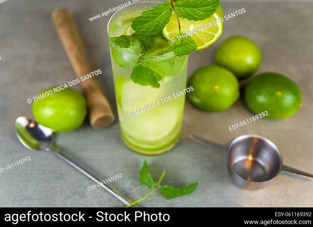 Mojito cocktail glass with mint and lime on a gray concrete background with fresh lime. Sparkling water and refreshing. place for text
