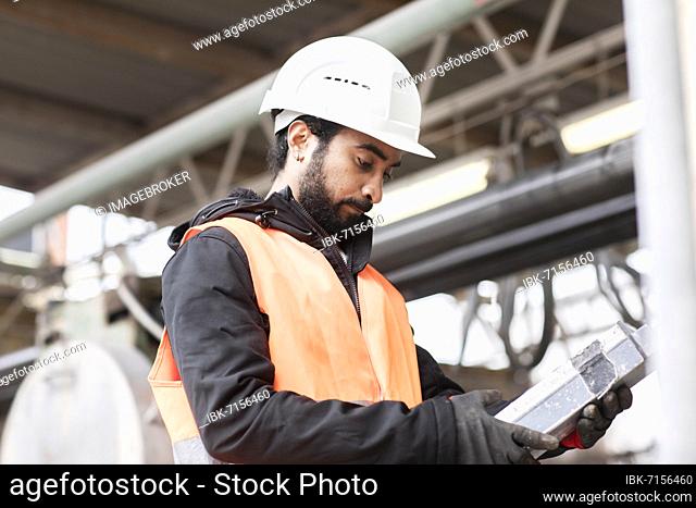 Technician with beard and helmet works in a workshop, Freiburg, Baden-Württemberg, Germany, Europe