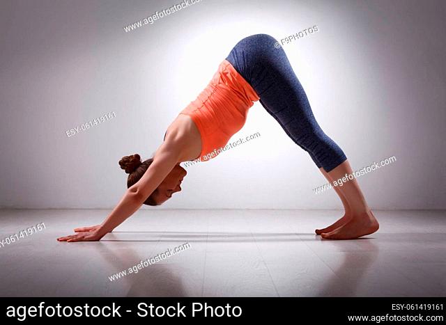 Beautiful sporty fit yogini woman practices yoga asana adhomukha svanasana - downward facing dog pose in studio