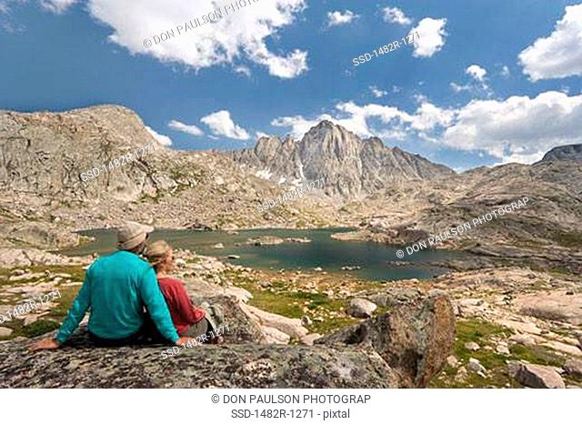 Hikers sitting on a rock and looking at the view, Indian Basin, Bridger-Teton National Forest, Wind River Range, Wyoming, USA
