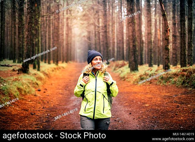 One young woman with a backpack in outdoor excursion leisure activity at the park. Female enjoying nature around smiling and doing trekking path