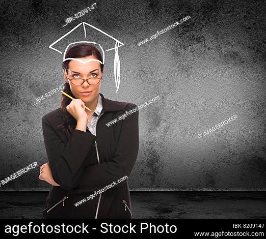 Graduation cap drawn on head of young adult woman with pencil in front of wall with copy space