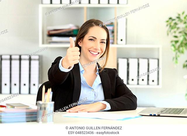 Proud office worker posing with thumbs up looking at camera