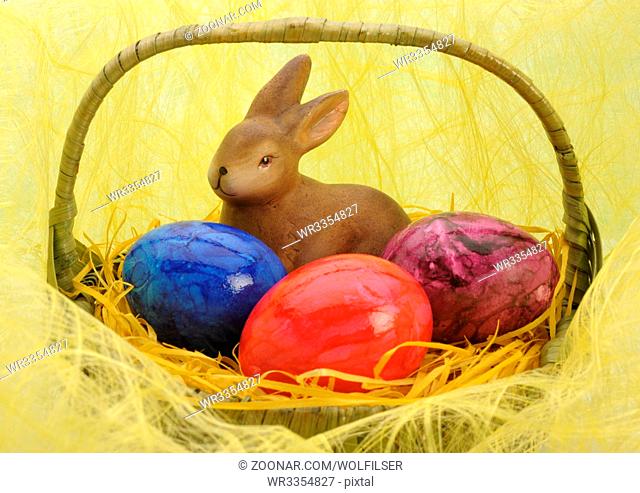 bunny and three painted eggs in easter nest