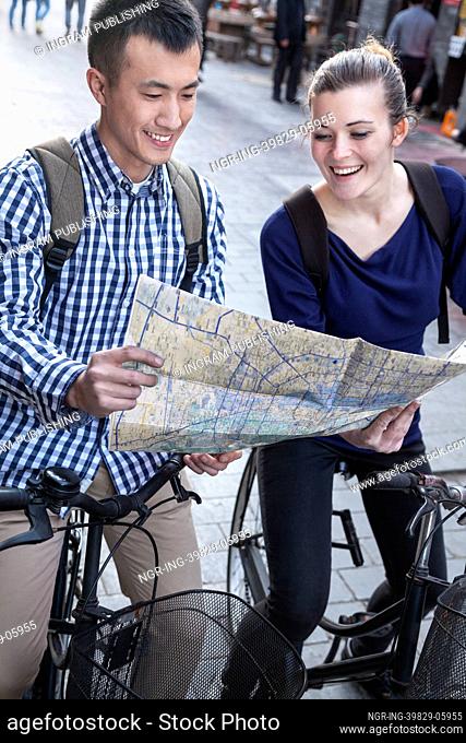 Young man and woman on bicycles, looking at map