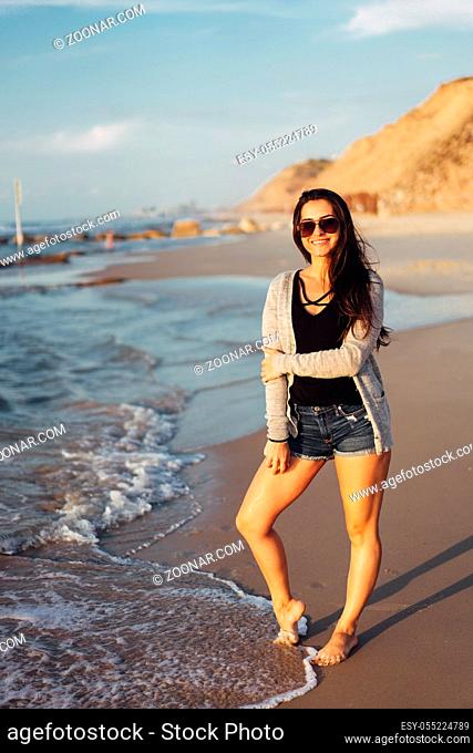 Girl walking along the beach. Caucasian woman walks along beautiful seashore