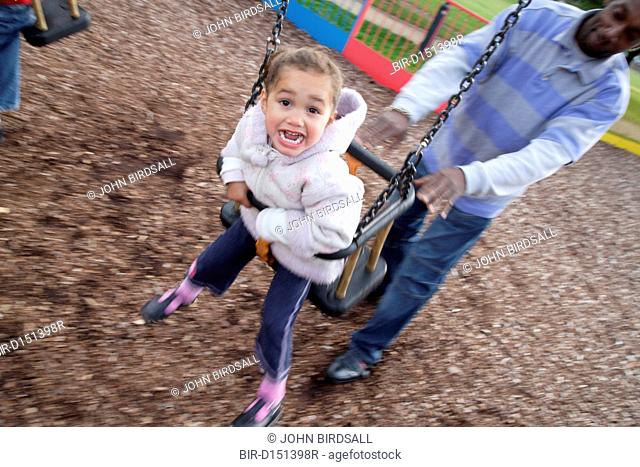 Man pushing boy on a swing