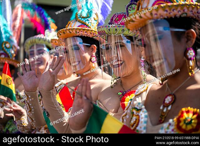 18 May 2021, Bolivia, La Paz: Women in traditional dress wave flags of Bolivia during a cultural event where the traditional ""Morenada"" is danced