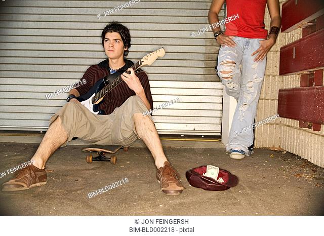 Young man playing guitar for money